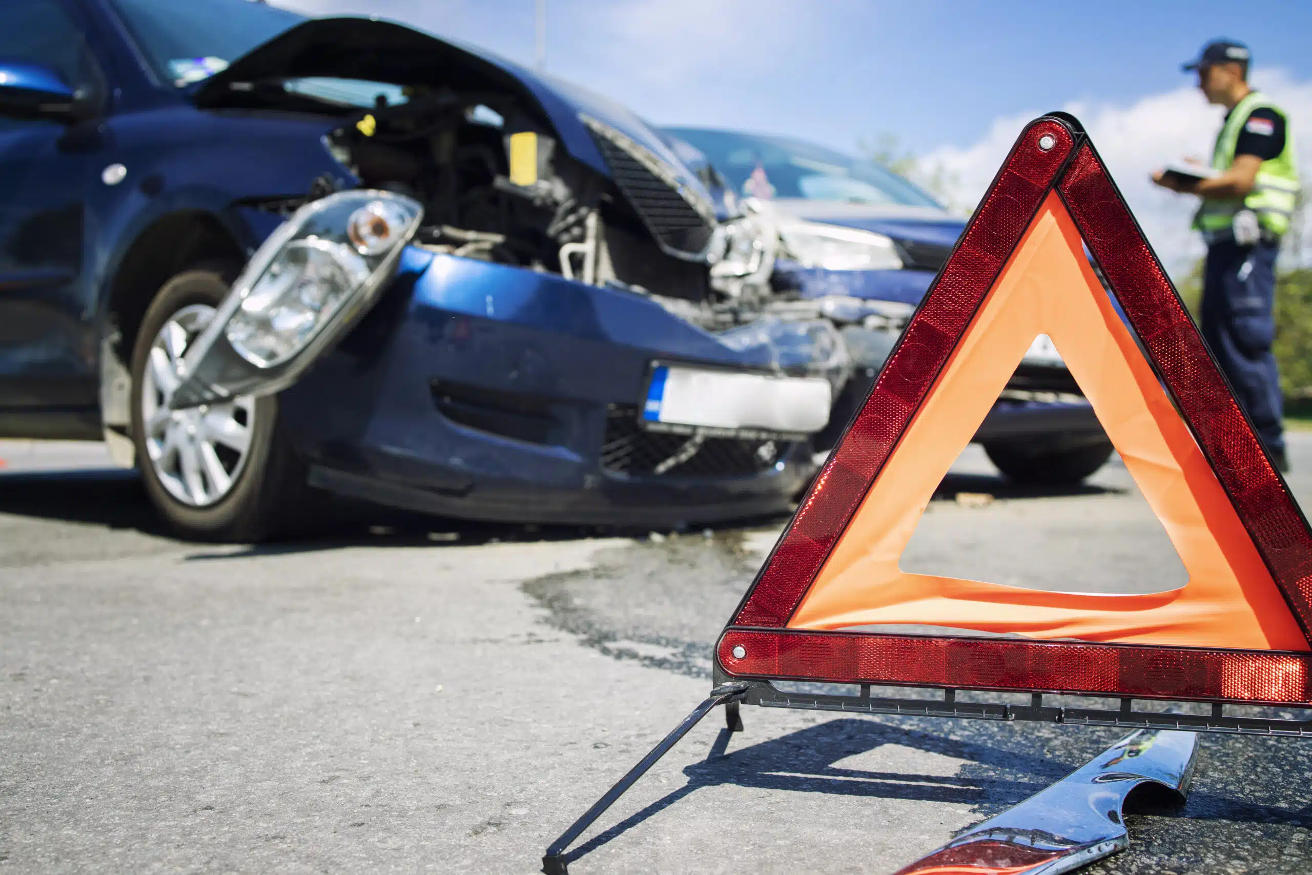 Road accident with smashed cars and a caution sign